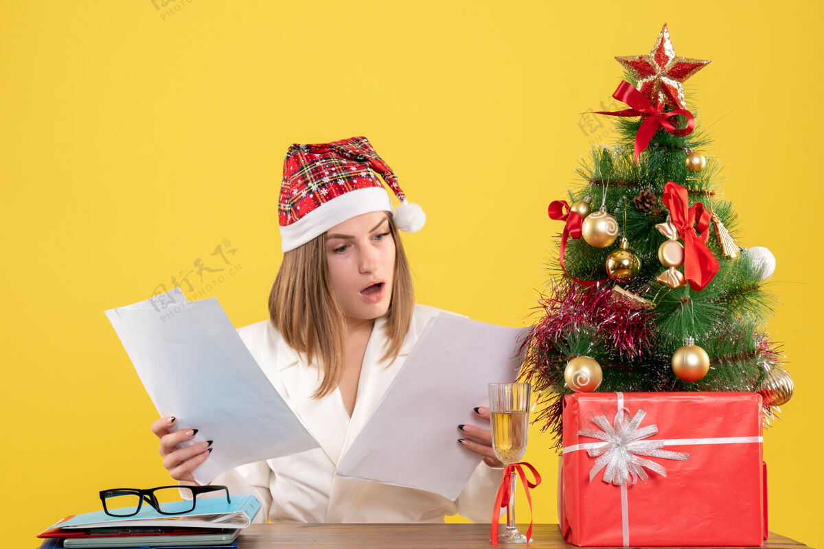 情感前视图女医生坐在圣诞礼物持有黄色背景文件健康快乐礼物