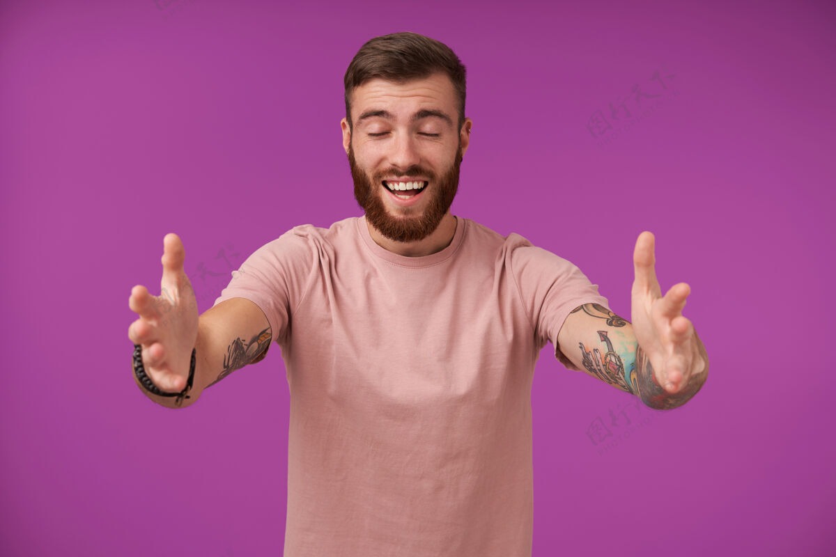 留胡子长着快乐的棕发胡须 有纹身的男性 张开双臂站在紫色的地面上 拥抱并闭上眼睛拥抱室内情绪