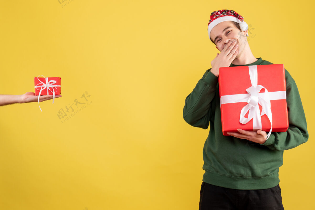 手正面图：拿着大礼物的年轻人站在黄色的人手里拿着礼物大幸福人