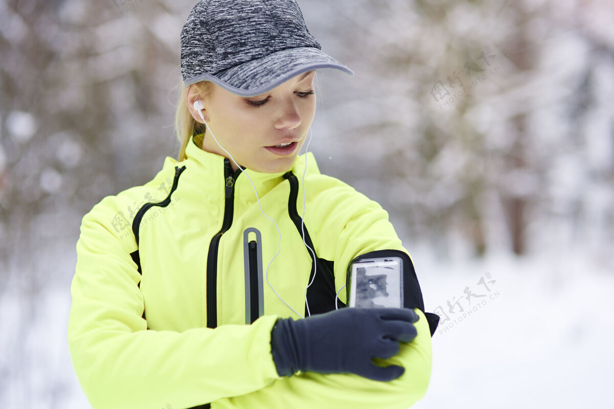 寒冷女运动员检查她燃烧了多少卡路里训练移动耳机