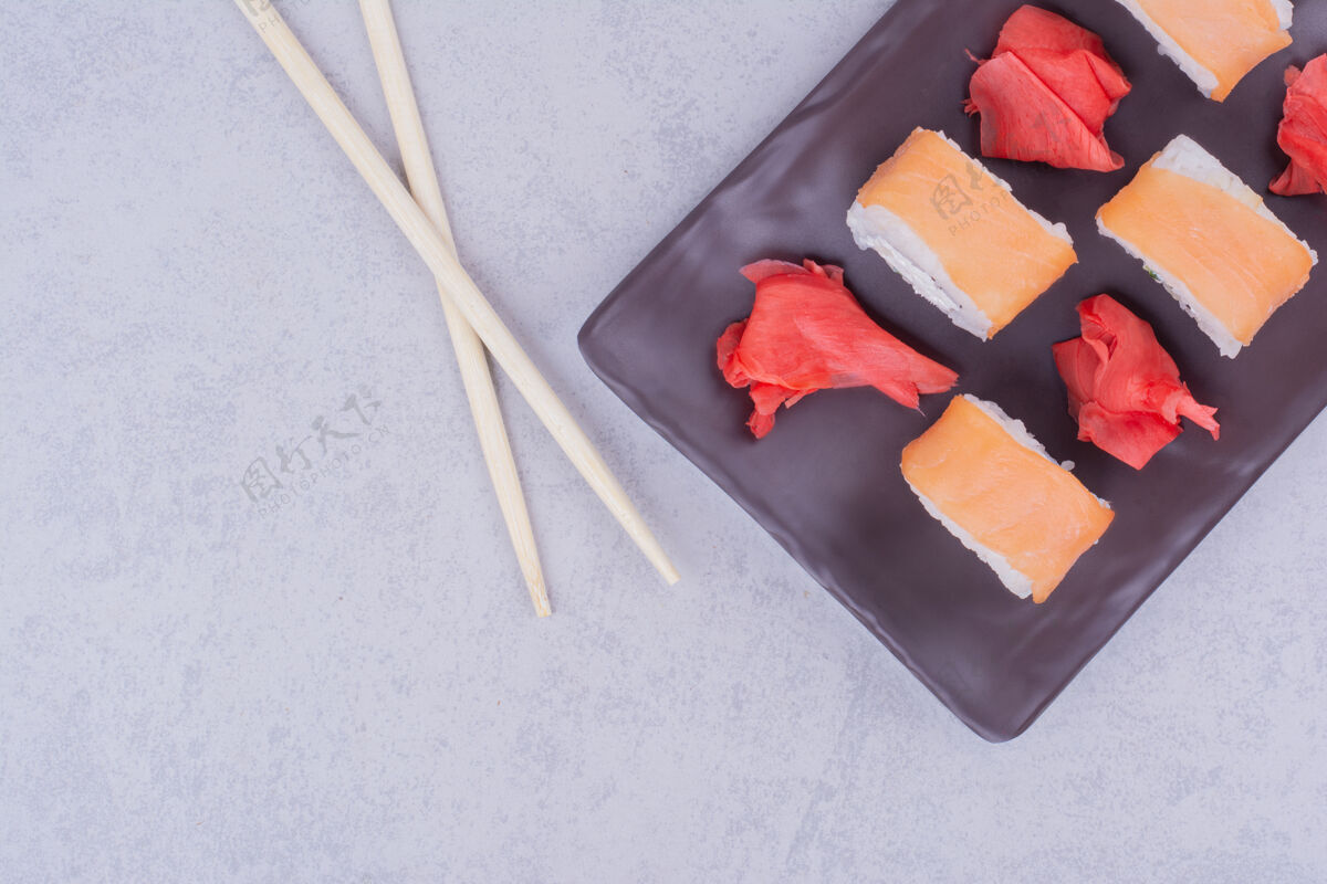 食品三文鱼卷和红腌姜放在一个黑盘子里膳食生物质量