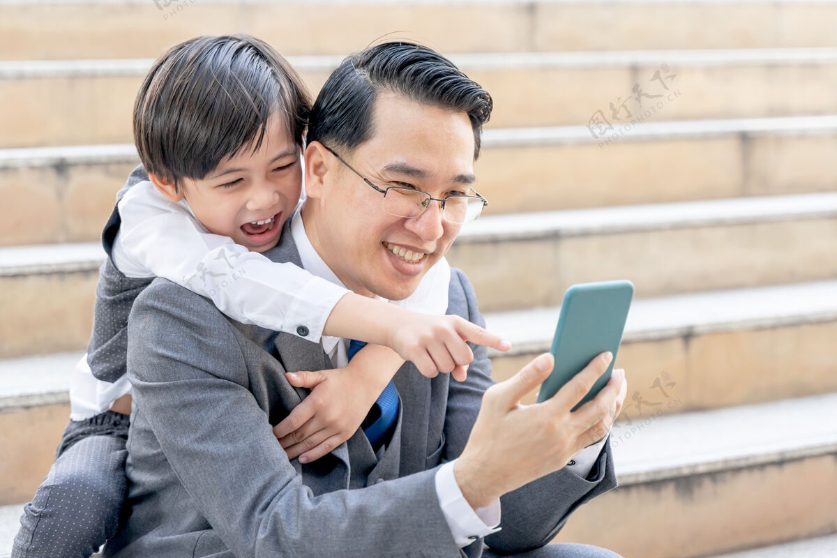 儿子父子俩在市区商业区一起玩智能手机商业通信孩子