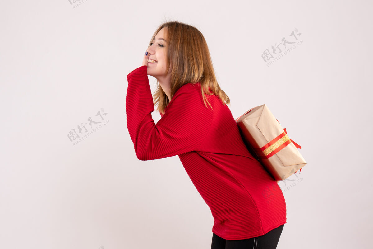 年轻的女人正面图：年轻的女性把礼物藏在背后情感节日人