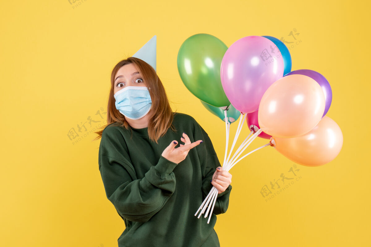五颜六色正面图：手持彩色气球的年轻女性生日幸福女人