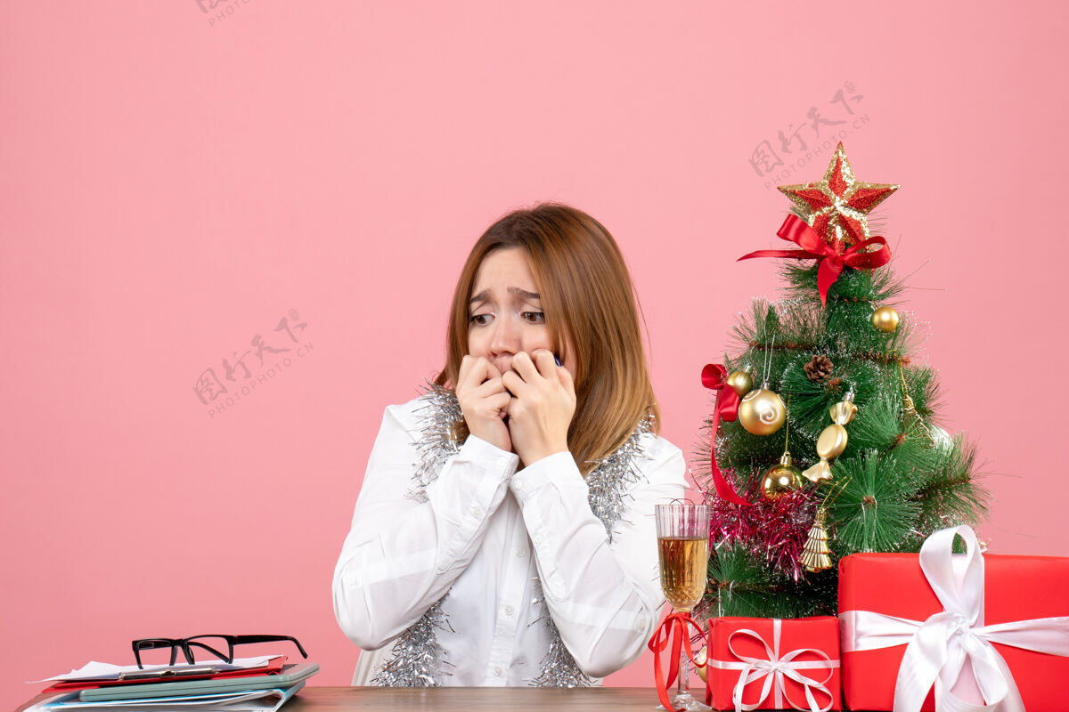 肖像女工围坐在粉色的圣诞礼物旁的正视图坐着圣诞节成人