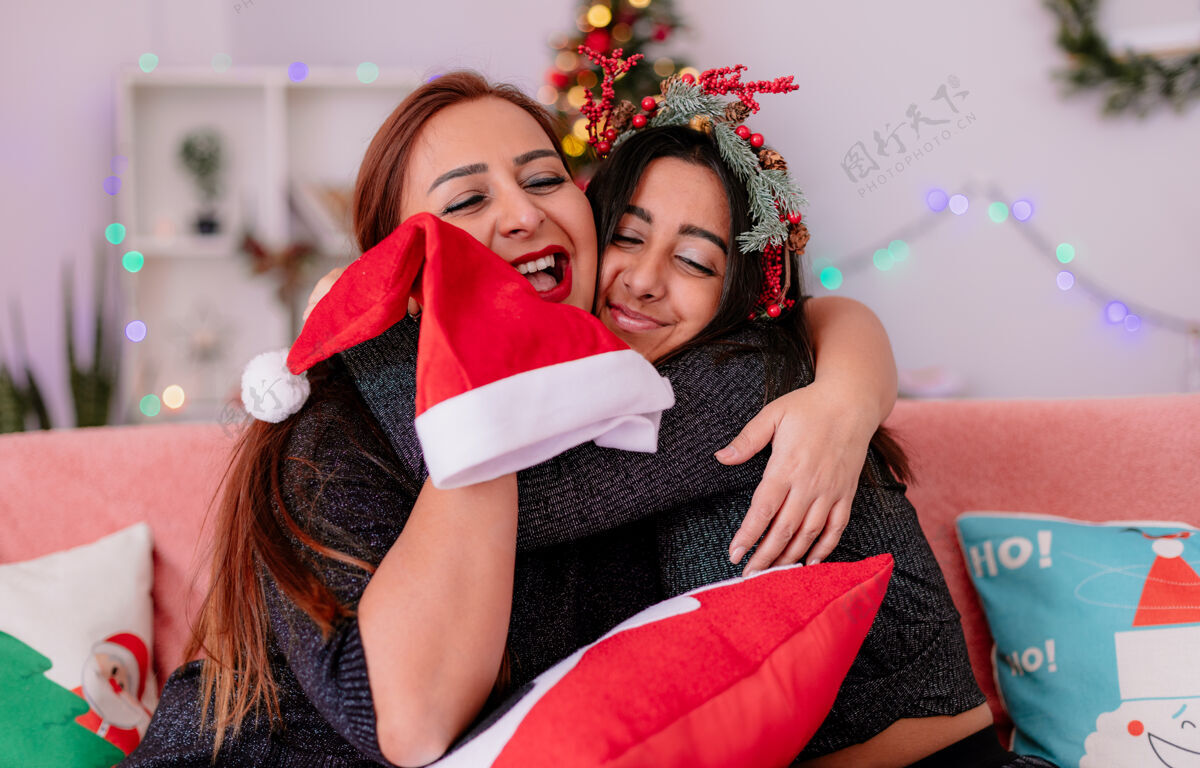 母亲可爱的女儿和妈妈坐在沙发上互相拥抱 在家里享受圣诞节时光沙发圣诞节爱