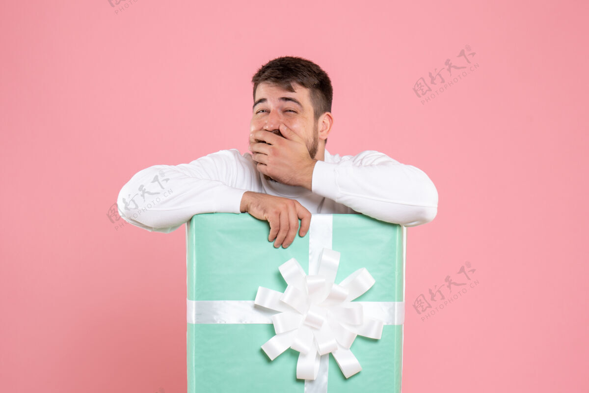 男人粉红色墙上礼物盒内年轻人的正面图快乐微笑盒子