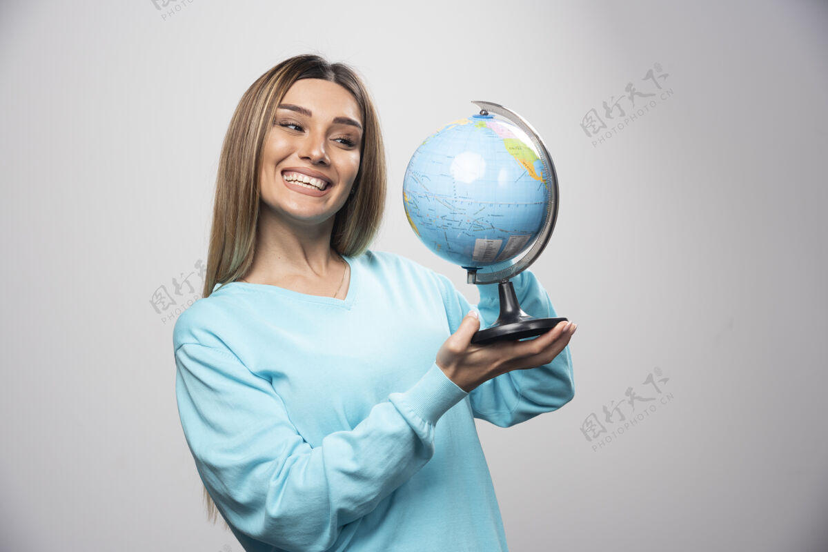 人类穿着蓝色运动衫的金发女孩拿着一个地球仪 猜测地点 玩得很开心休闲人教育
