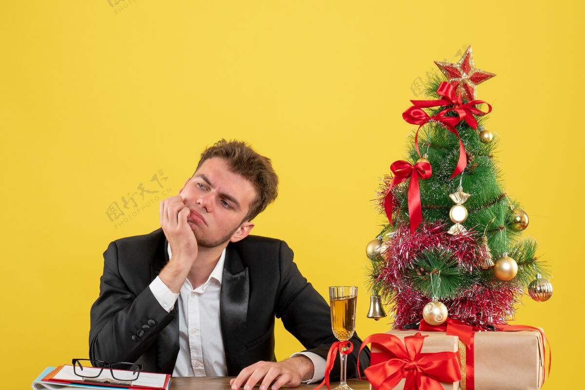 圣诞节正面图：坐在工作场所后面思考黄色的男工人坐年情绪