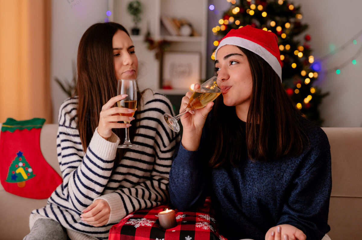 圣诞快乐可爱的年轻女孩坐在扶手椅上喝着香槟 在家里享受圣诞节时光漂亮香槟享受