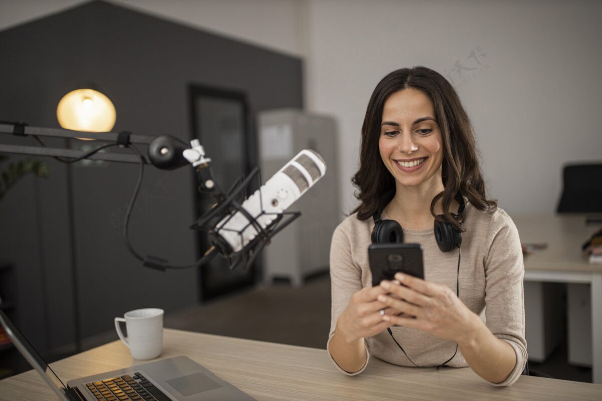 媒体笑脸女人用麦克风和智能手机在电台做播客水平广播女人