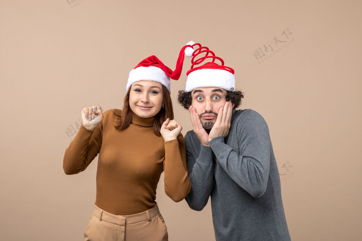 男性节日喜庆和派对理念-快乐可爱惊喜的年轻情侣穿上彼此团结的圣诞老人帽子可爱肖像