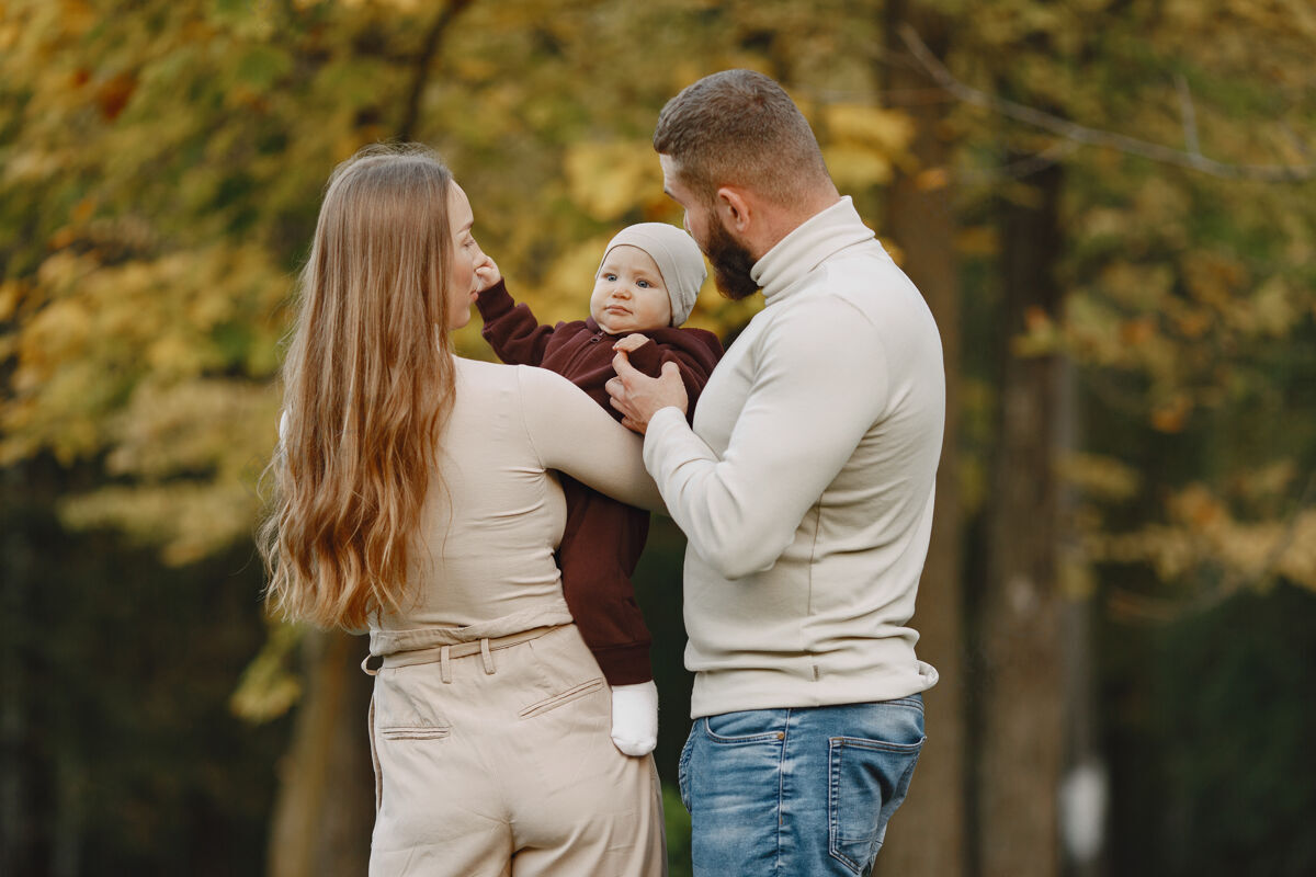 毛衣秋天公园里的一家人穿棕色毛衣的男人和父母在一起的可爱小女孩快乐关系三个