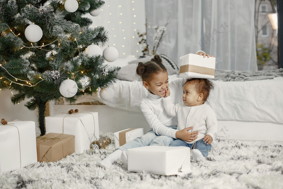 童年穿着白色毛衣的孩子女儿们在圣诞树旁缝线两个姐妹在家传统金发女儿