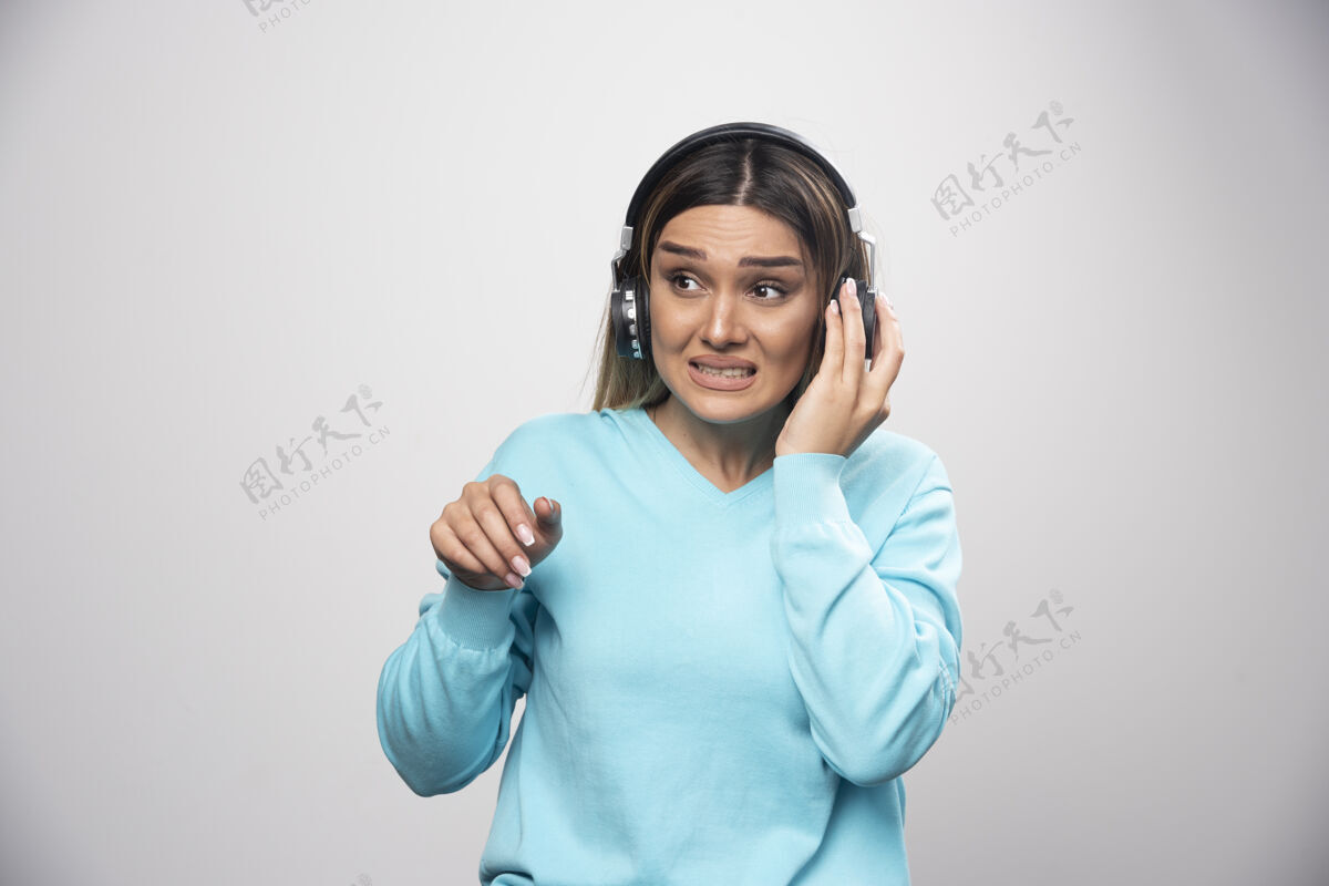 女性穿着蓝色运动衫的金发女孩戴着耳机摆姿势耳机活力耳机