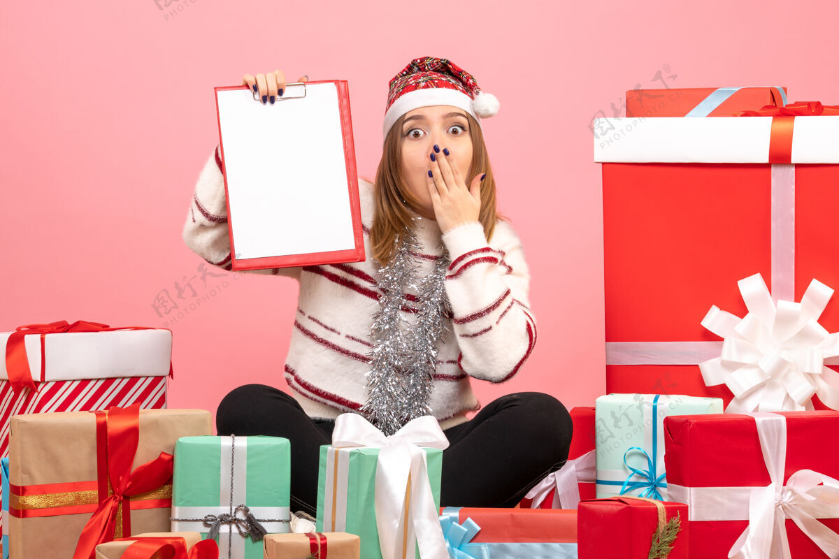 粉色前视图年轻女性围坐在圣诞节礼物与文件说明女性年轻女性节日