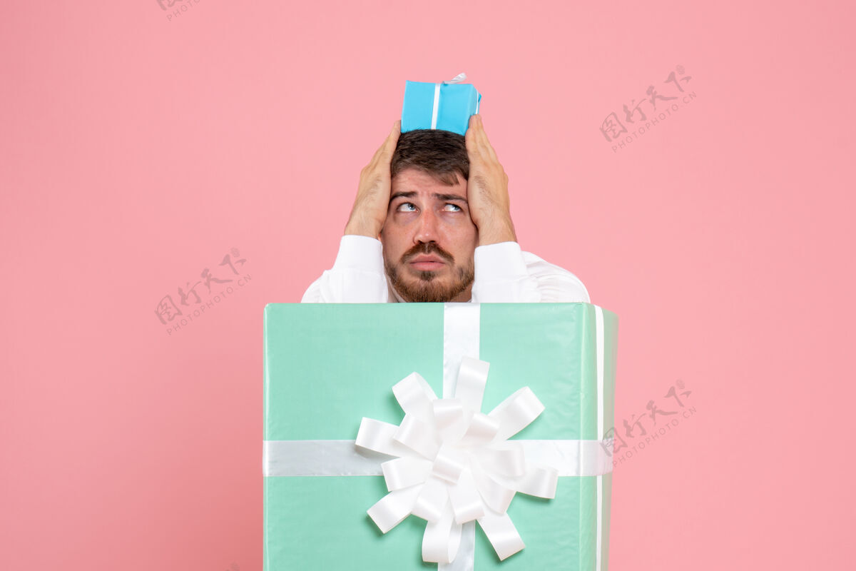 盒子礼物盒内年轻人的正面图 粉红色的墙上挂着小礼物情感礼物游戏