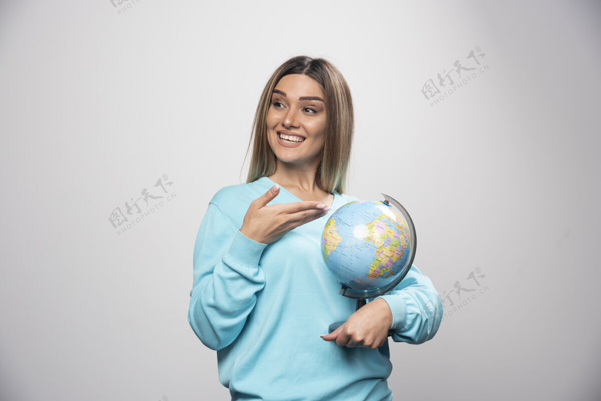 微笑穿着蓝色运动衫的金发女孩拿着一个地球仪 猜着地点 玩得很开心目的地地球旅行