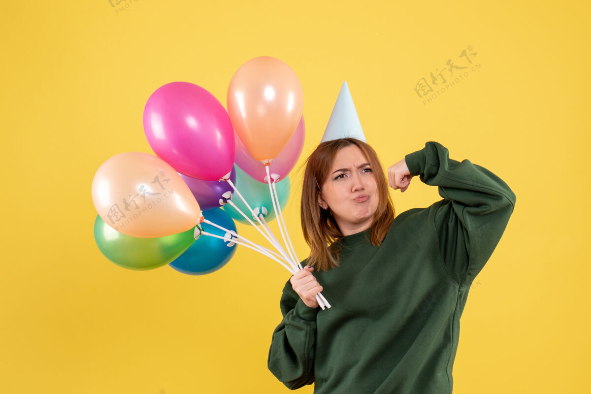 乐趣正面图是一位年轻的女士 手里拿着五颜六色的气球聚会节日飞机