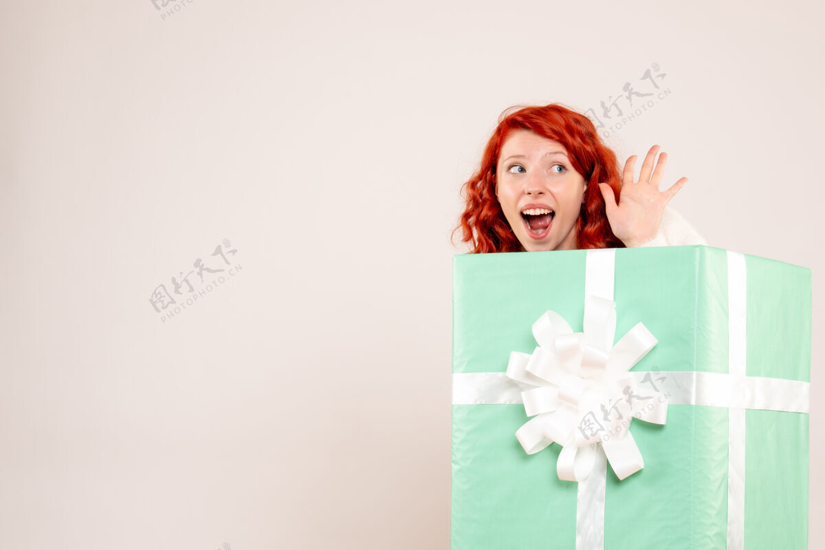 丝带隐藏在白墙上的年轻女子的正面视图人礼品盒漂亮