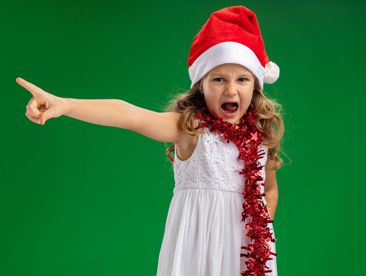 小愤怒的小女孩戴着圣诞帽 脖子上有花环 边上有点隔离 绿色的墙上有复制空间侧面点脖子