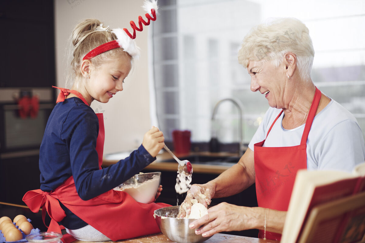 庆祝可爱的女孩在奶奶的帮助下做饭围裙指导圣诞节