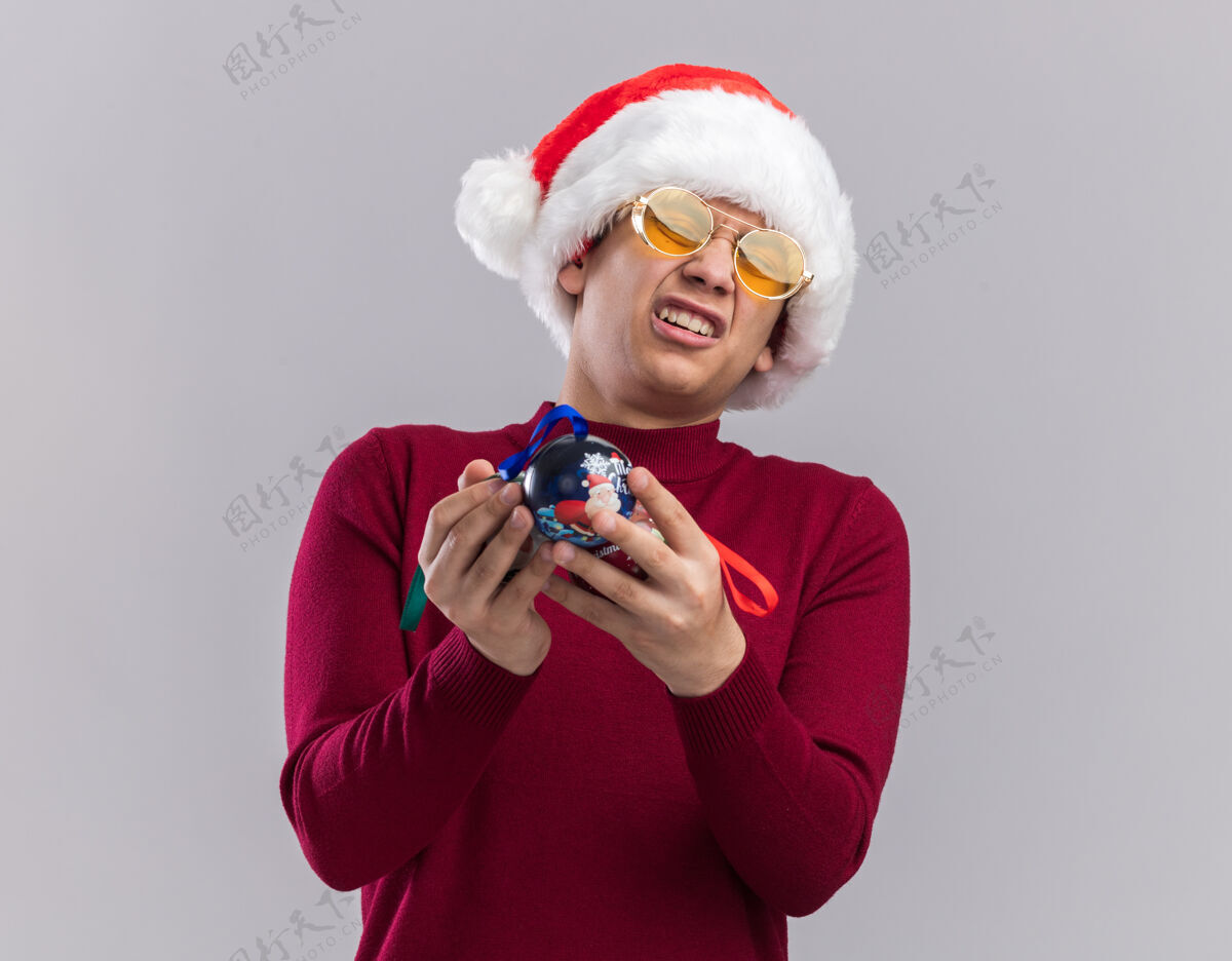 圣诞节遗憾的是那个戴着圣诞帽戴着眼镜拿着圣诞树球的年轻人被隔离在白色背景上树球抱着