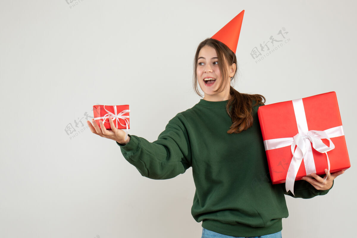 举行戴着派对帽的快乐女孩在白色衣服上送圣诞礼物礼物礼物人们