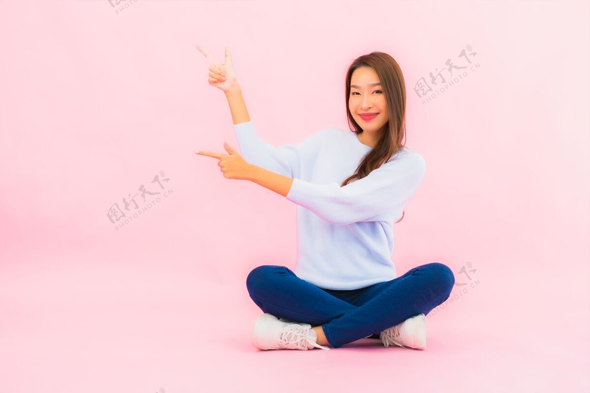交易肖像美丽的亚洲年轻女子坐在粉色隔离墙的地板上成功座位欢迎
