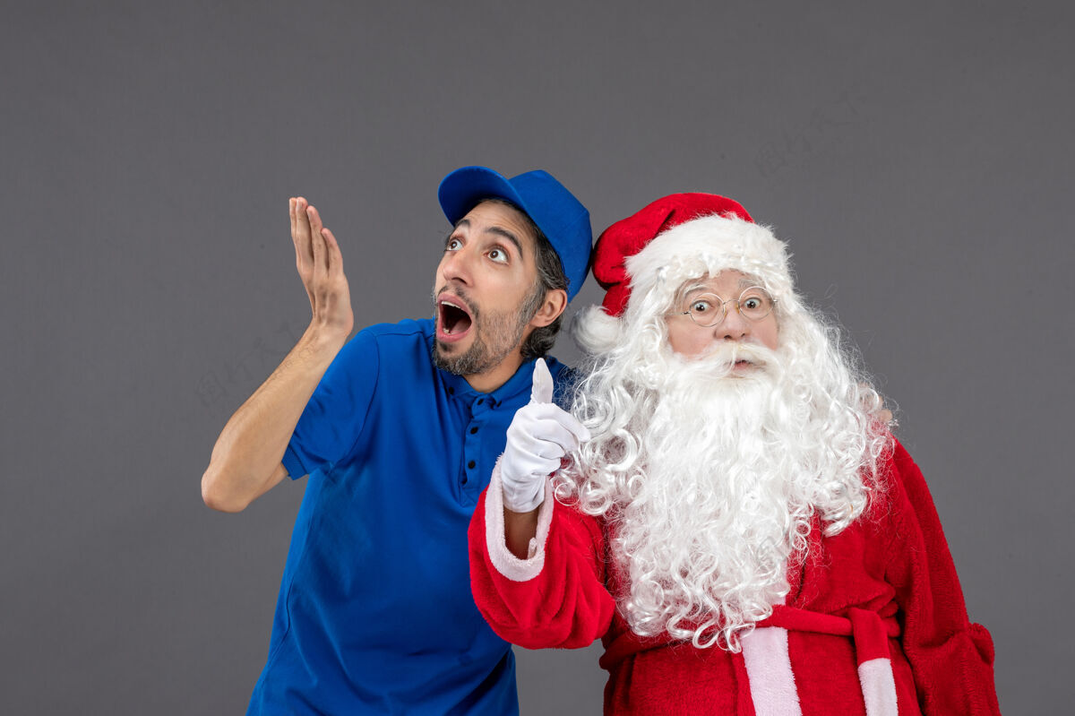 圣诞老人灰色墙上的圣诞老人和男信使的正面图服装信使圣诞