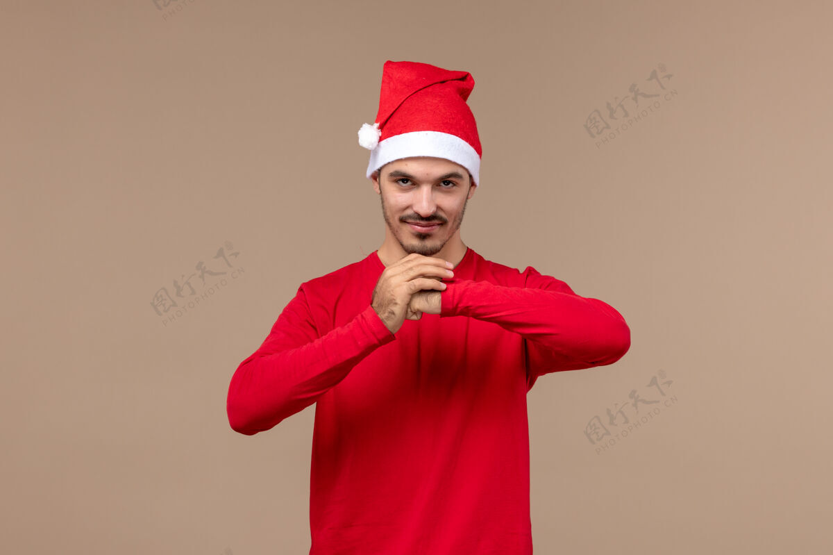 年轻男性正面图：年轻男性 表情平静 背景为棕色 圣诞节情感假期帽子冷静微笑