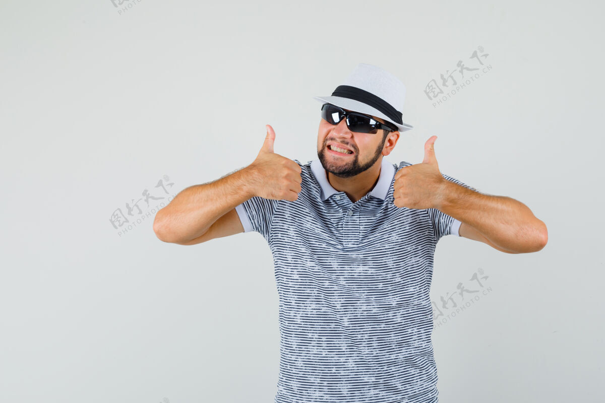 肖像穿着t恤 戴着太阳镜的年轻人竖起大拇指 看上去很满意 正面视图工作室衬衫手势