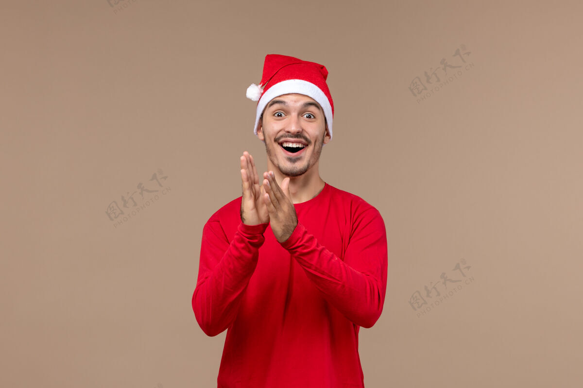 漂亮正面图：年轻男性 在一个棕色背景的圣诞假期里 表情激动节日微笑男性