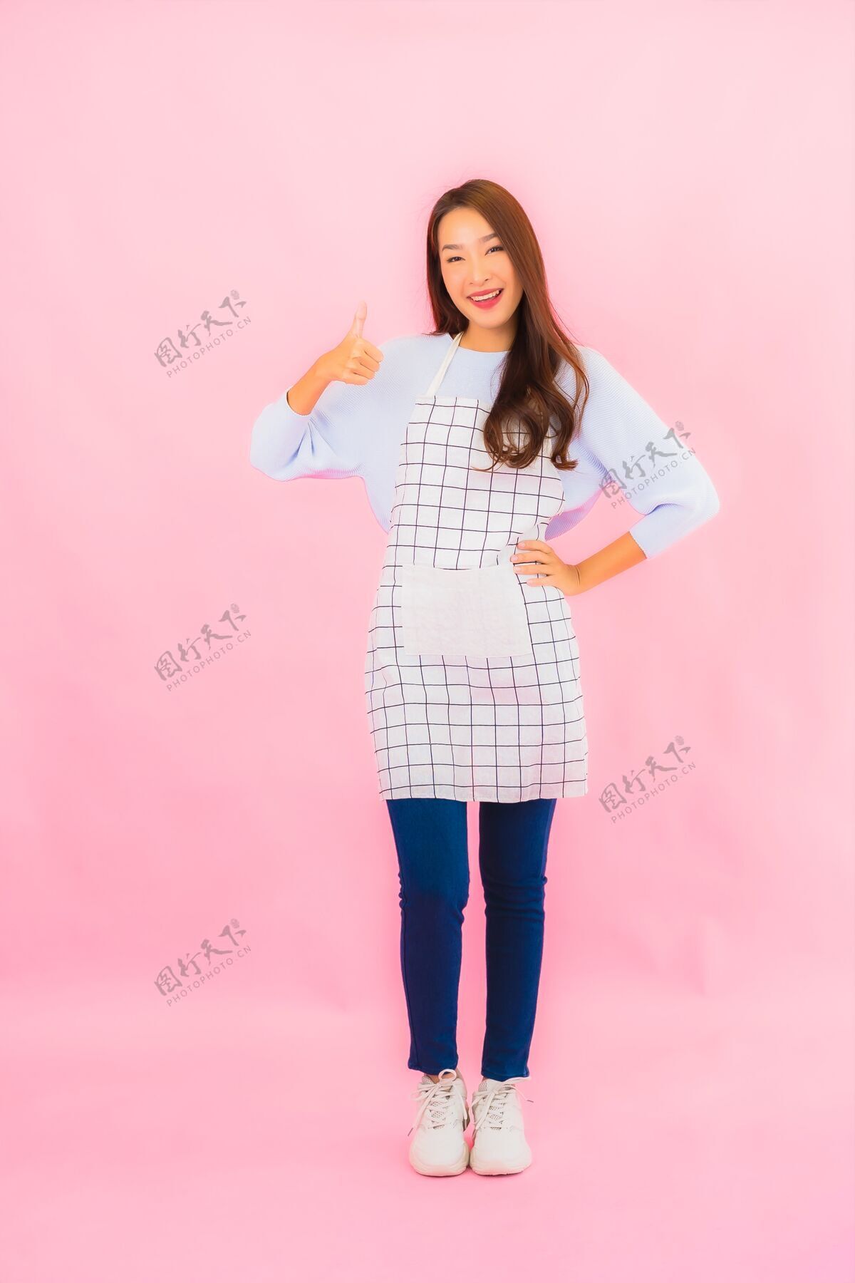 圆点肖像美丽的亚洲年轻女子在厨房穿着围裙在粉红色的隔离墙上中国人完美厨师