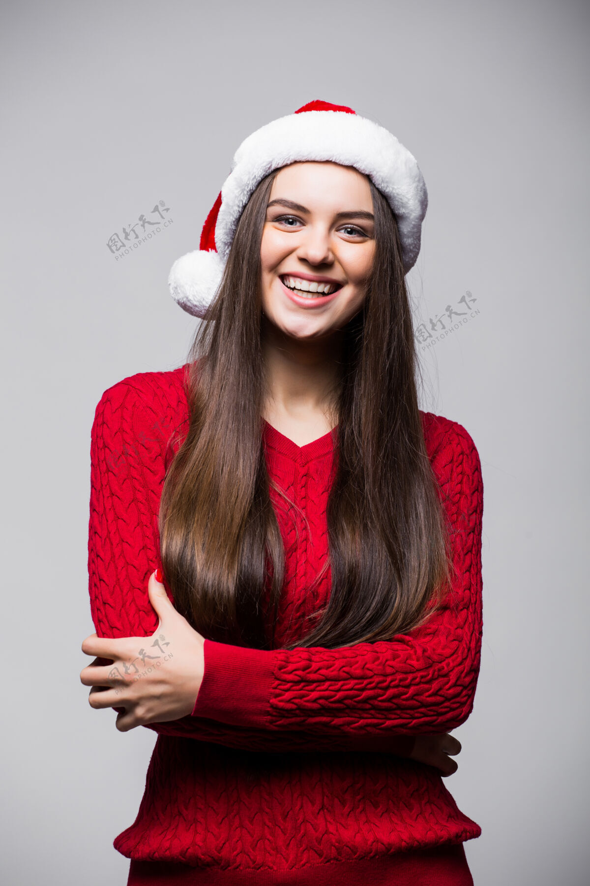 快乐可爱的年轻白人妇女戴着圣诞帽和手套对着浅灰色的墙壁微笑圣诞节和新年的概念复制空间可用兴奋帽子圣诞老人