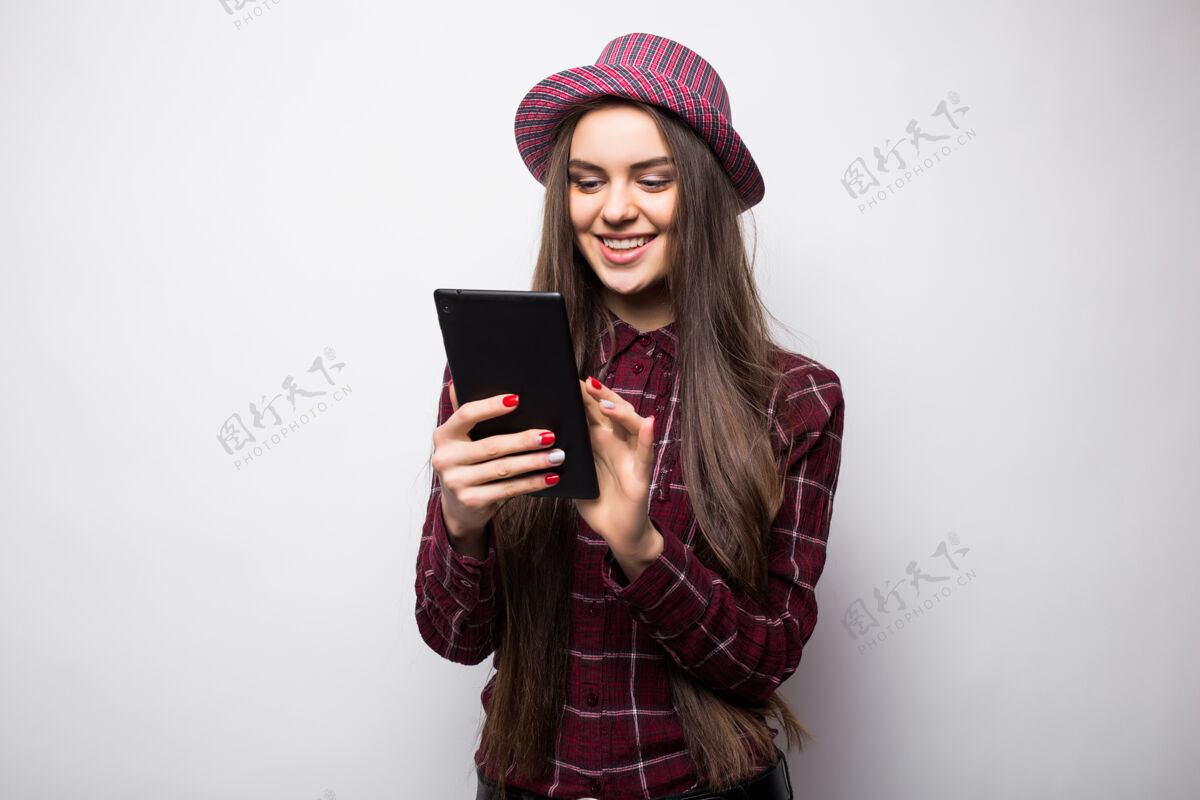 触摸屏隔离在白墙上拿着平板电脑的女人在触摸屏上工作随意微笑的白种女人肖像便携式数码