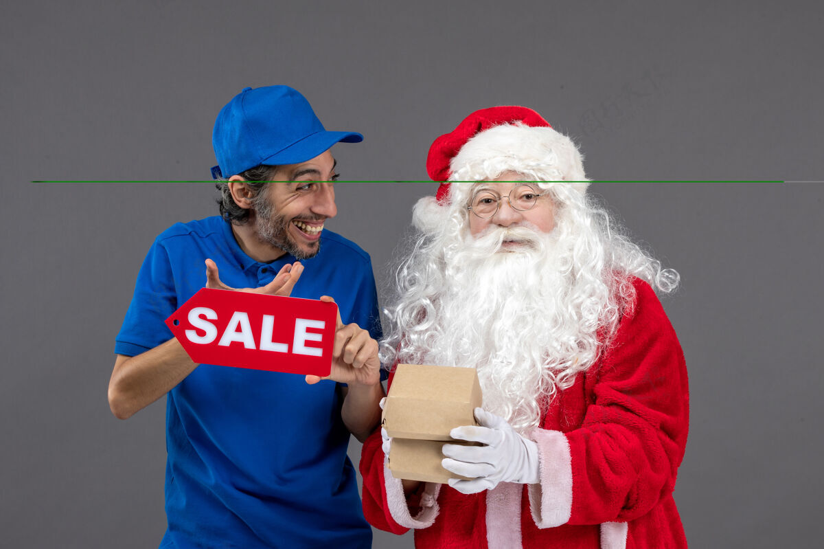快乐圣诞老人的正面图 男信使手持销售横幅 灰色墙上有食品包装肖像男性圣诞老人