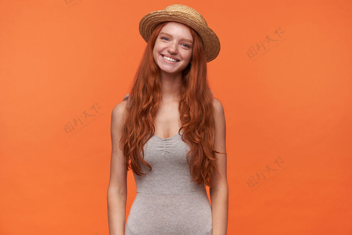 衬衫横向写真 可爱快乐的年轻女性 卷曲的狐毛孤立在橙色背景下 穿着休闲服 头戴草帽 积极的情感概念年轻牙齿女性