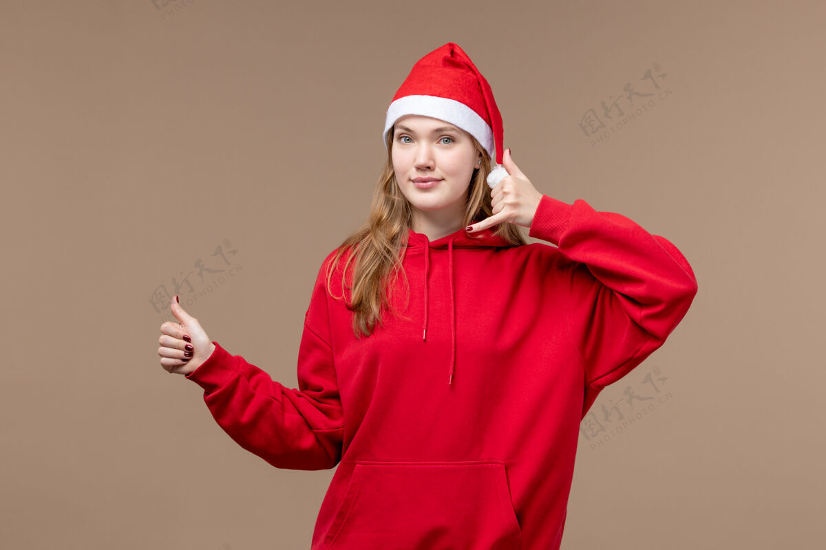 快乐正面图：年轻女性在棕色背景下微笑着摆出圣诞情感假期的姿势节日人情感
