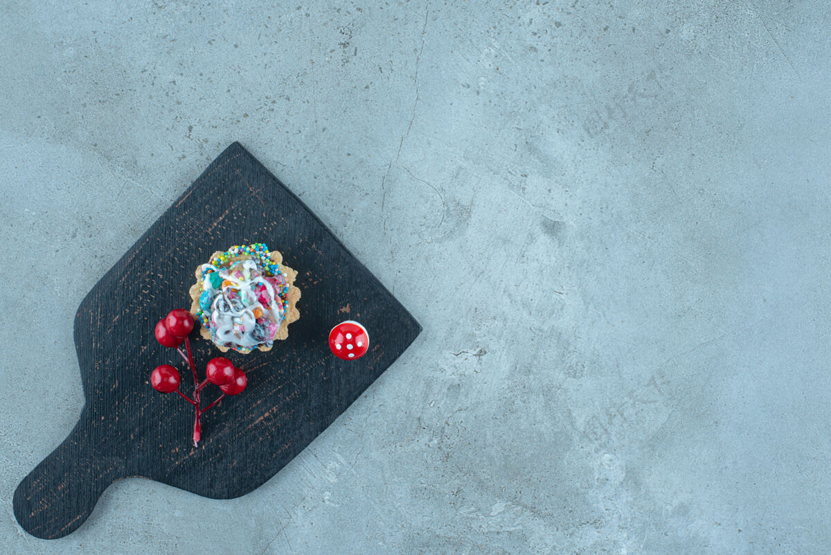 圣诞节在一块黑色的大理石板上放上糖果和圣诞装饰品的纸杯蛋糕糖顶级美味