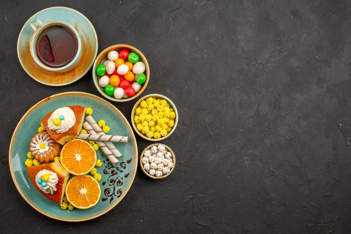 早餐顶视图美味的派片与新鲜的橘子和一杯茶在黑暗中杯子餐糖果