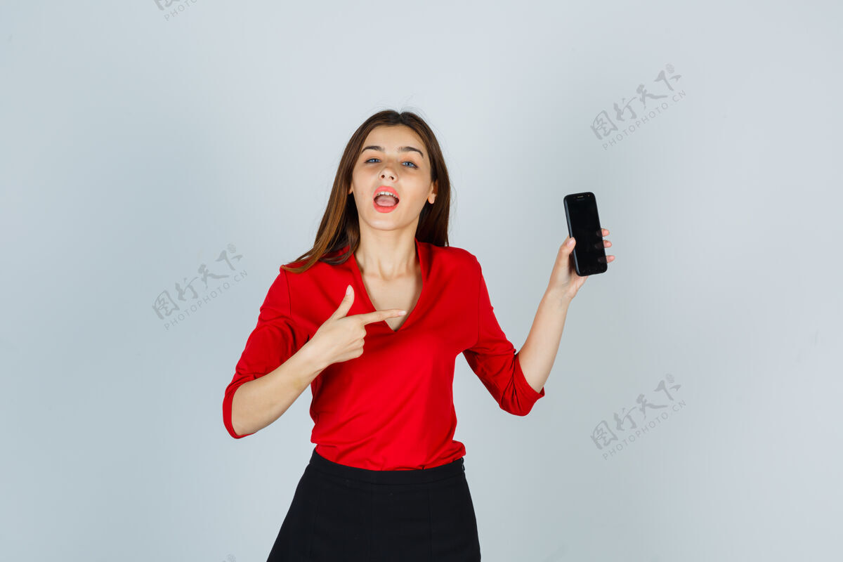 友谊穿着红色上衣的年轻女士指着手机的画像年轻快乐青春