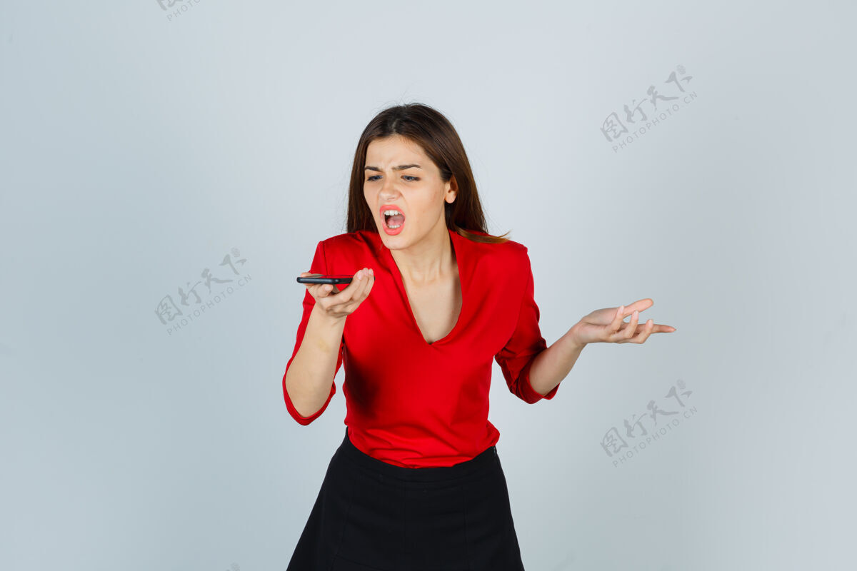 严重一位穿着红色上衣 裙子 表情愤怒的年轻女士在手机上录制语音信息女人声音漂亮