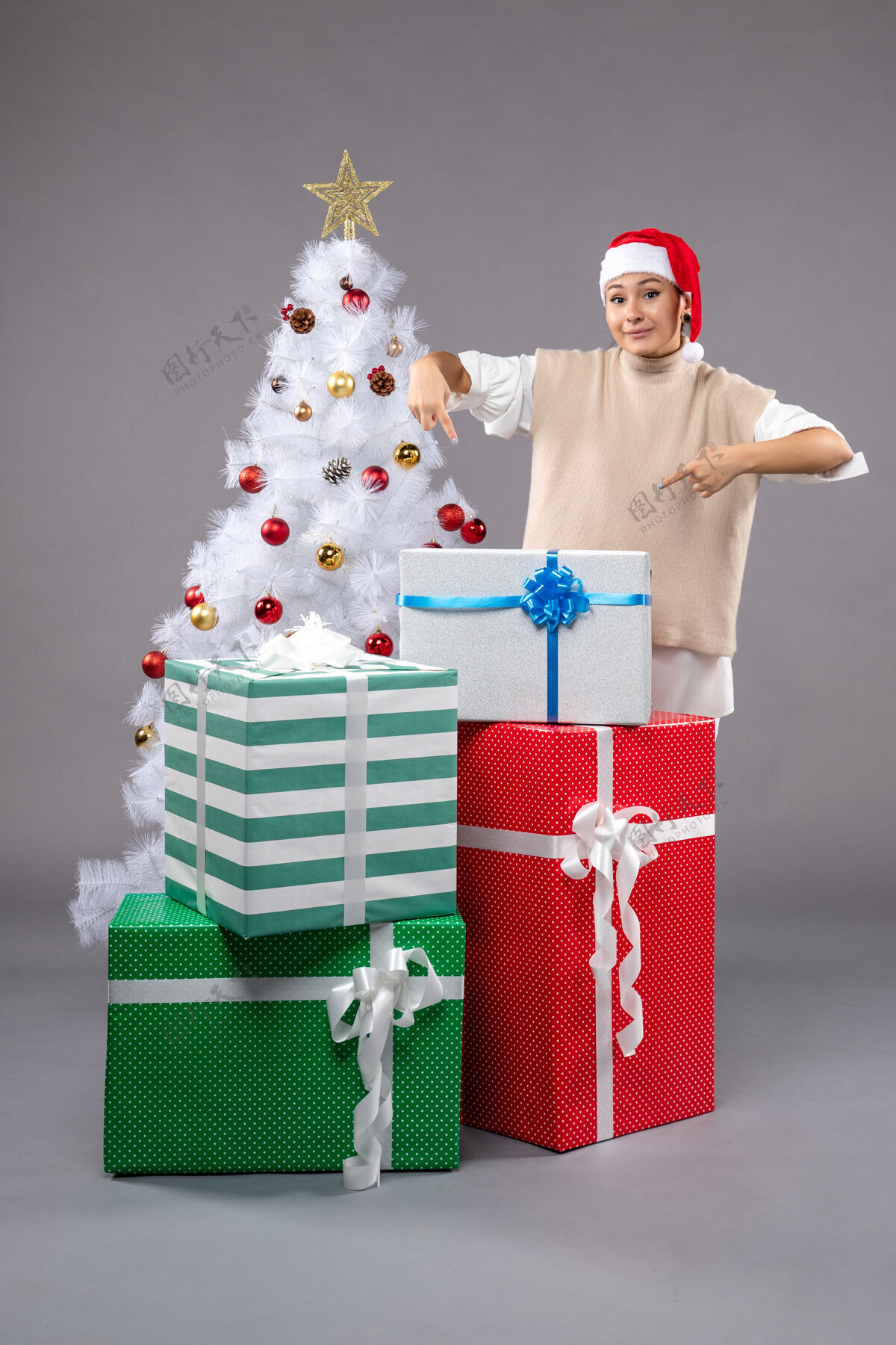 购物在灰色的圣诞礼物周围有漂亮的女人圣诞老人帽子礼物