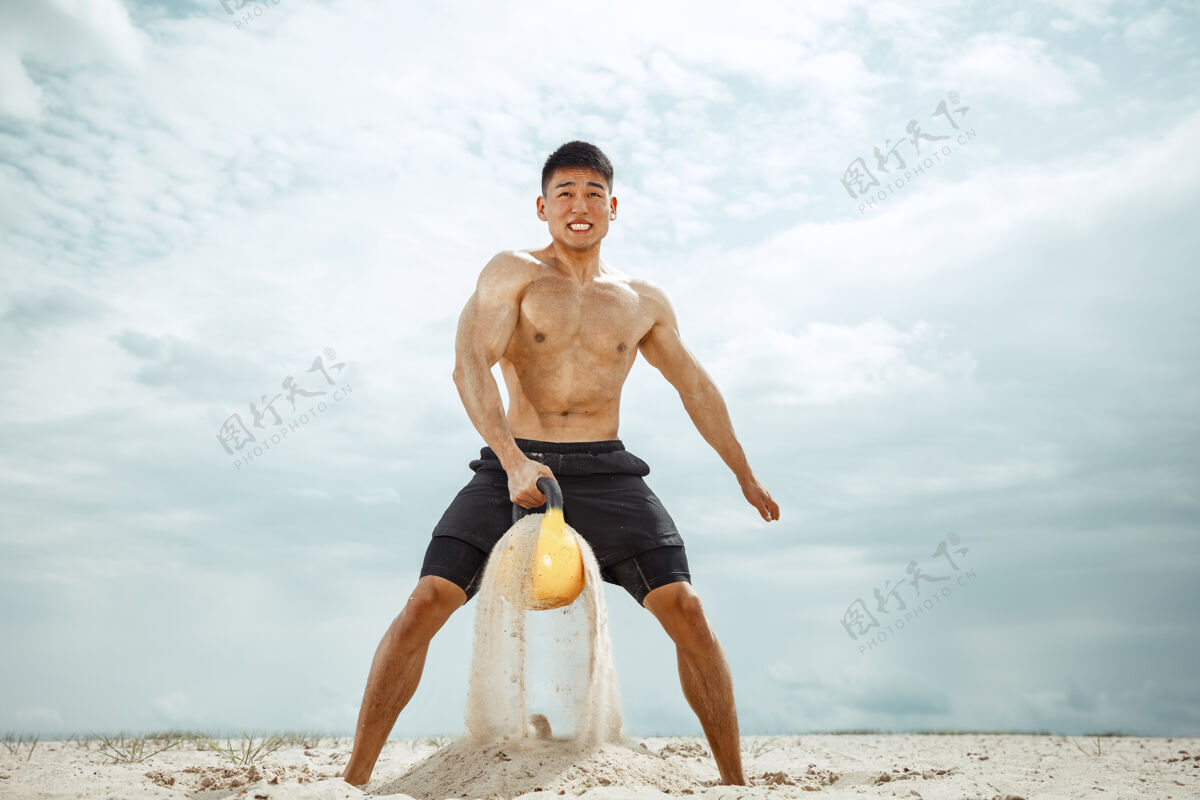 锻炼年轻健康的男子运动员在海滩上做深蹲健身白种人强壮