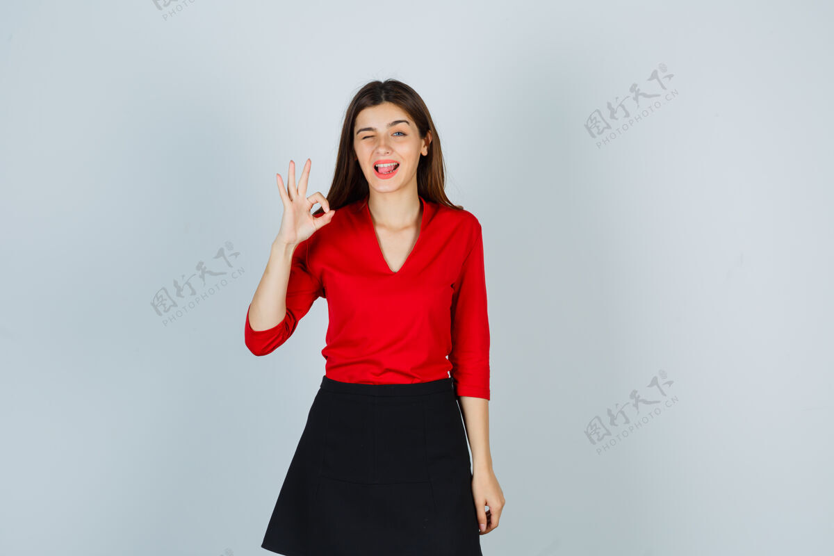 房间一个年轻的女人 穿着红色的衬衫 露出了舌头欢快裙子休闲