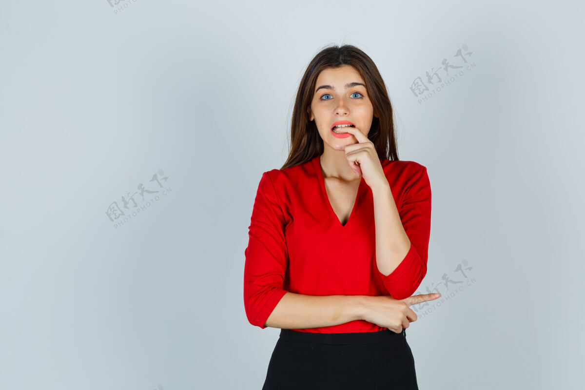 随意穿着红衬衫的年轻女士 摆姿势时咬着裙子的手指 看起来很健忘手指压力人