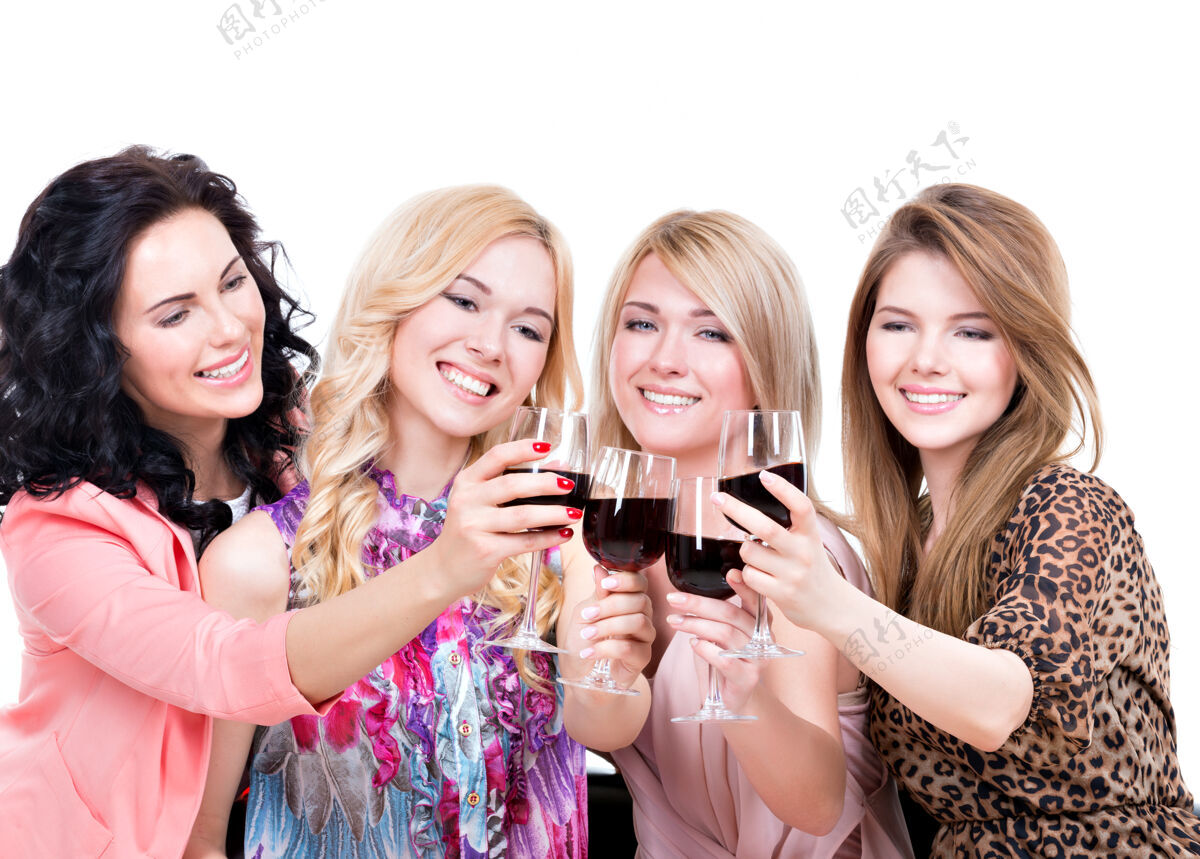 大笑年轻快乐的女人们尽情享受和喝红酒的画像-孤立于白色之上四牙齿女性