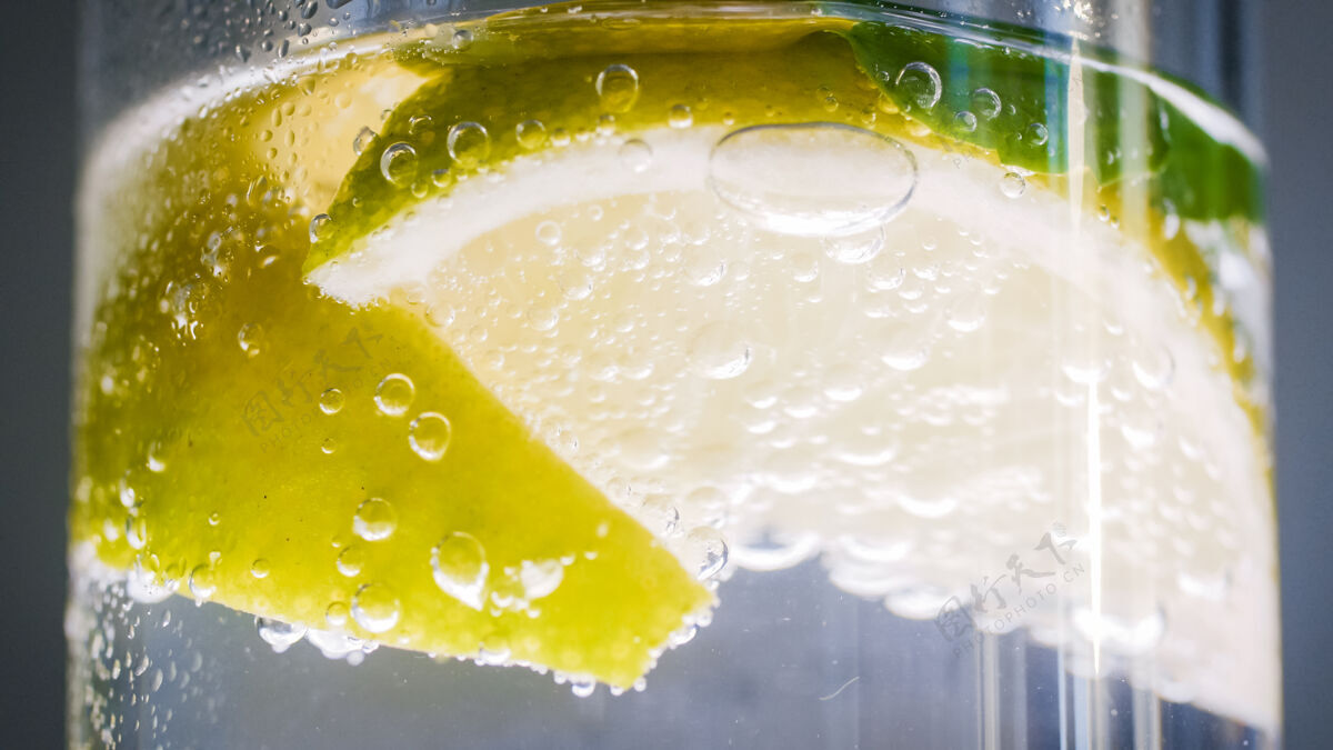 工具气泡和柠檬片漂浮在冷柠檬水中的特写照片汽水柠檬水