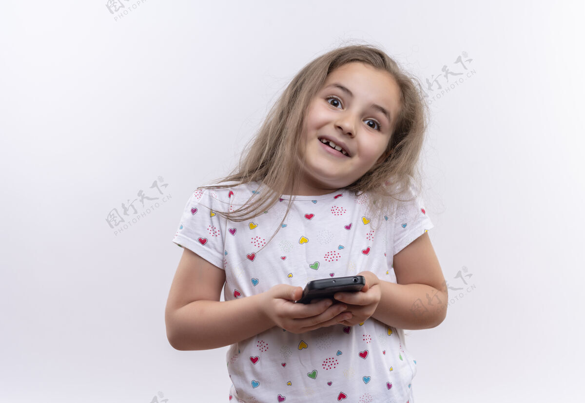 小微笑的小女孩穿着白色t恤拿着电话在孤立的白色背景白色电话学校